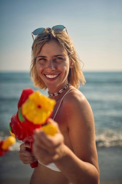 Genç bir kız güzel bir yaz gününde sahilde oynarken fotoğraf için poz veriyor. Yaz, sahil, deniz, tatil