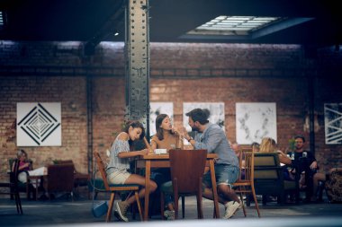 Genç arkadaşlar modern bir kafeteryada sohbet edip kahve içiyorlar. Çift, arkadaşlar, öğrenciler..