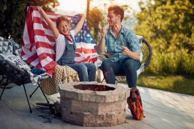 Baba ve güzel genç kızı titreyen alevlerin yanında oturup, kızartılmış şekerlemelerin tadını çıkarıyorlar. Sıcak ve neşe atmosferinde, kız gururla Amerikan bayrağı sergiliyor..