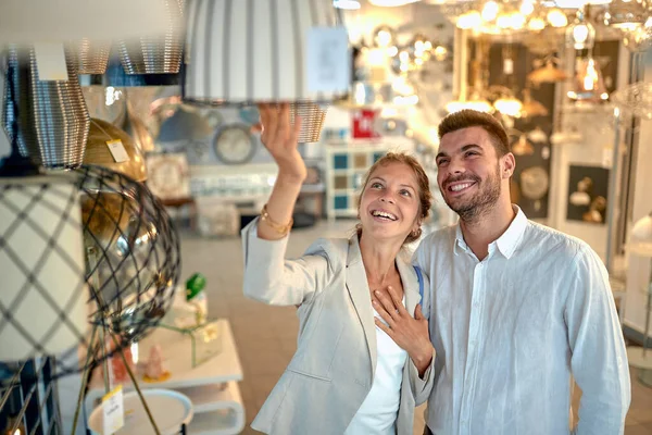 Usmívající Mladý Pár Vybírá Lampu Moderním Ateliéru Domácí Výzdoby Manželka — Stock fotografie