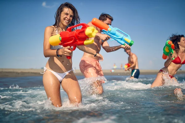 Mujer Alegre Con Pistola Agua Amigos Vacaciones Juntos Jugando Orilla —  Fotos de Stock