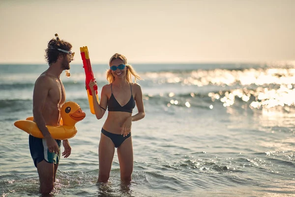 若いカップルは 美しい夏の日にビーチの浅い場所でおもちゃで遊ぶのに楽しい時間を過ごしています ビーチ — ストック写真