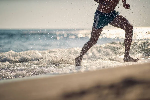 筋肉のハンサムな男が水の中を走るときに輝く水の滴 — ストック写真