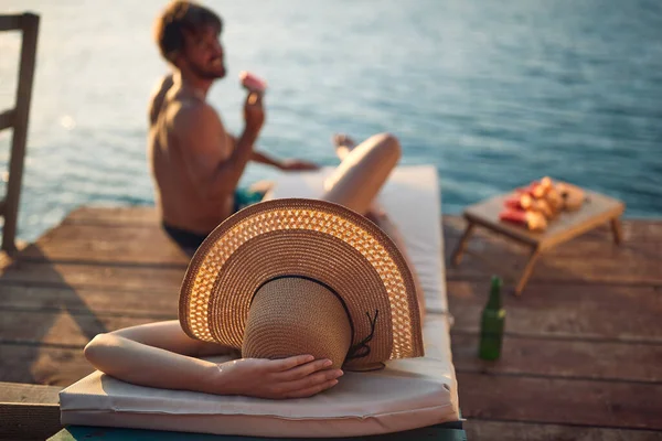 在一个美丽的夏日 一对身穿泳衣的年轻夫妇在河岸上聊天和晒日光浴 — 图库照片