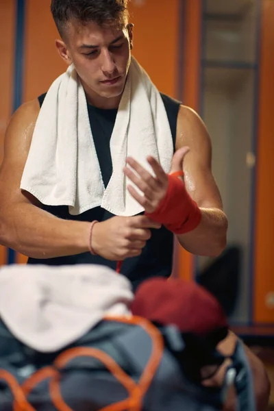 肌肉发达的年轻人把红色的防护带绑在手上准备拳击 体育概念 — 图库照片