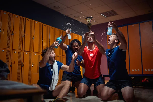 四人组队员在更衣室里一起庆祝胜利 一起拿着金牌 一起欢呼雀跃 一起泼水 团队精神 — 图库照片
