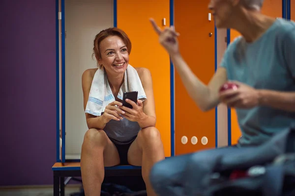 穿着运动服的年轻漂亮的女人坐在体育馆更衣室里 享受着与她朋友的对话 生活方式概念 — 图库照片