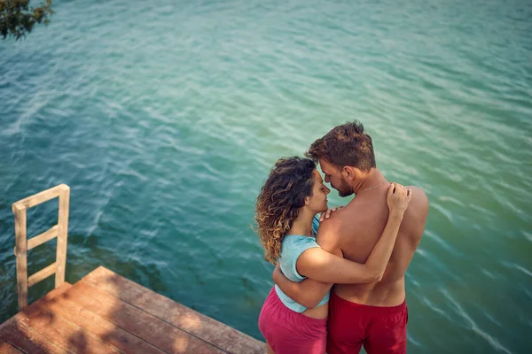 在一个美丽的夏日 一对恋爱中的年轻夫妇在河岸的码头上拥抱着 — 图库照片