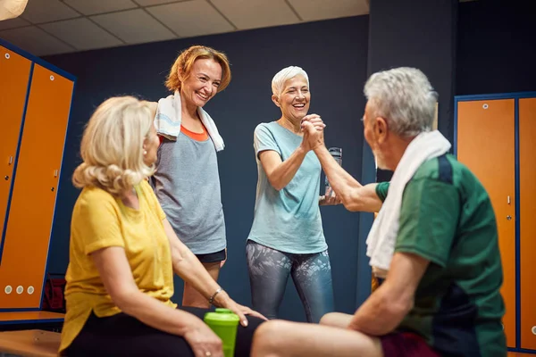 上了年纪的男女在体育馆更衣室里击掌 感觉精力充沛地锻炼身体 成熟的女人和年轻的女人为他们欢呼 健康概念 — 图库照片
