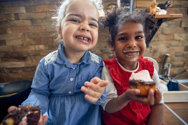 两个年轻姑娘在厨房里分享着欢笑和放纵的松饼 友谊的温馨联系在一起 — 图库照片