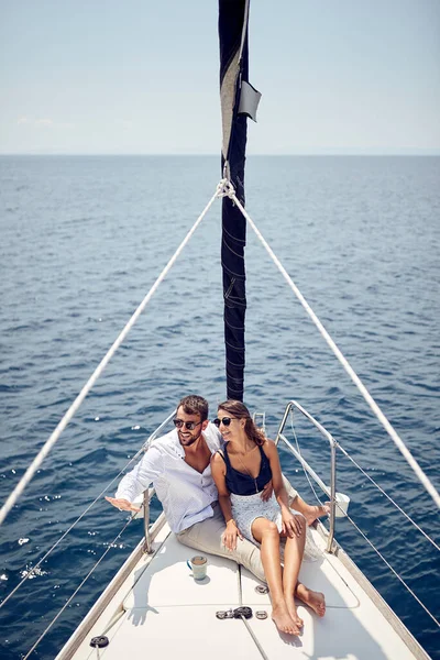 一对恋爱中的年轻夫妇坐在游艇的船头上 一边欣赏美丽的风景 一边在海上度过一个美丽的阳光灿烂的日子 人际关系 — 图库照片