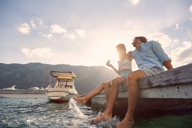 Aşağıdan genç bir çiftin deniz kenarında oturduğu ve güneşli bir günde sohbet ettiği bir manzara. Aşk, ilişki, tatil, deniz