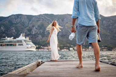 Lüks elbiseli güzel gelin kendini mutlu hissediyor. Şarabı ve bardağı olan damat. Balayında yeni evli bir çift. Düğün, balayı, aşk konsepti