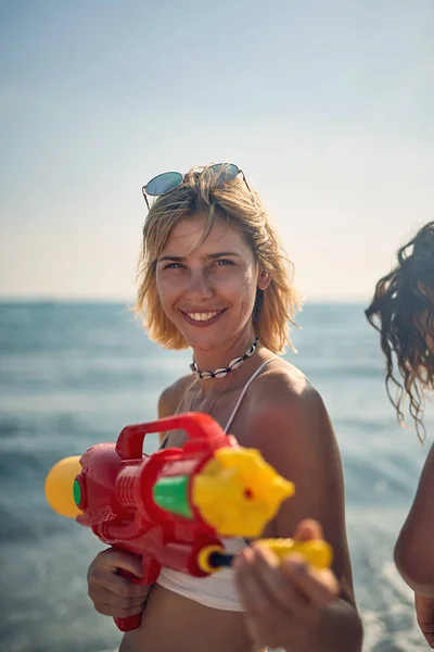 水銃を持つ笑顔の女の子は海でビーチで楽しんでいます — ストック写真