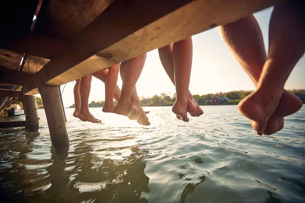 친구들 부두에 물에서 다리를 흔들며 즐긴다 — 스톡 사진