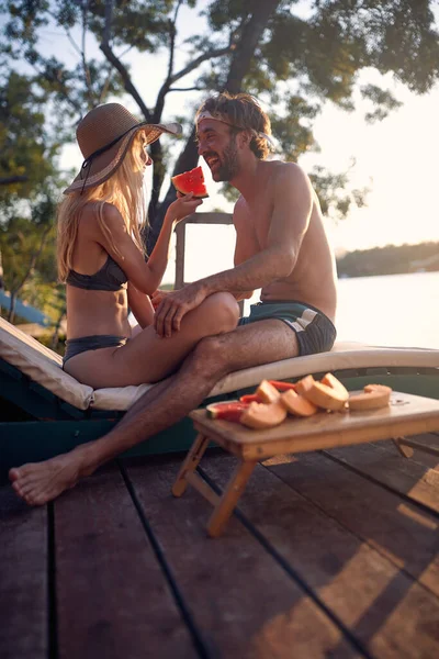 ロマンチックな幸せな男と女リラックスし 一緒に休日にスイカを食べる日没 — ストック写真