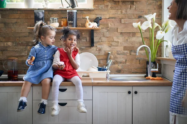Радостная Мама Смотрит Двух Милых Красивых Девушек Сидящих Кухонной Столешнице — стоковое фото