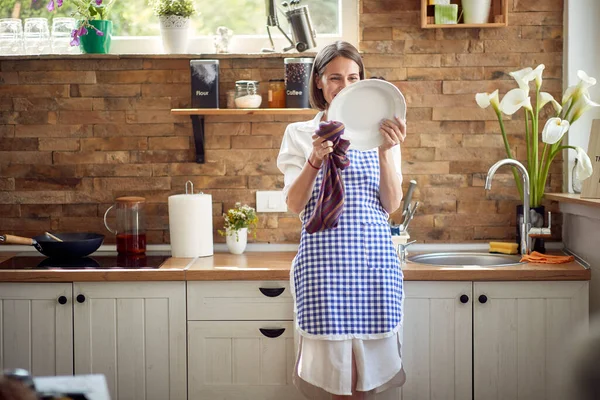 Красивая Молодая Домохозяйка Фартуке Стоящая Современной Кухне Вытирая Посуду Хлопковым — стоковое фото