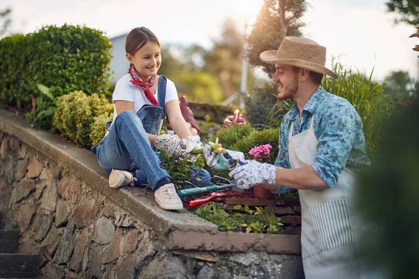 陽気な若い女の子は若い男を助ける 晴れた夏の日に屋外で庭を持つ父 雑草の切断 植え付け ライフスタイルの概念 — ストック写真