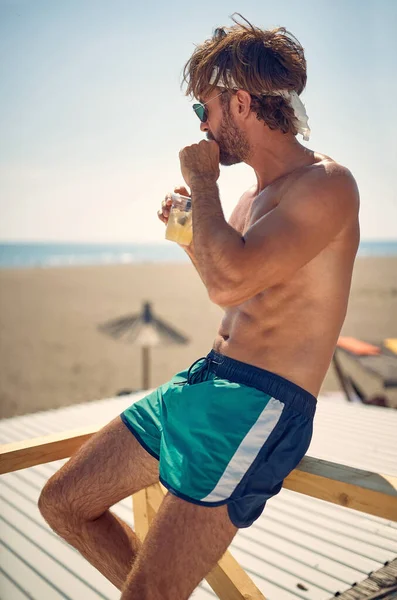 Молодой Красивый Мужчина Пляже Потягивает Напиток Смотрит Сторону Воды Человек — стоковое фото