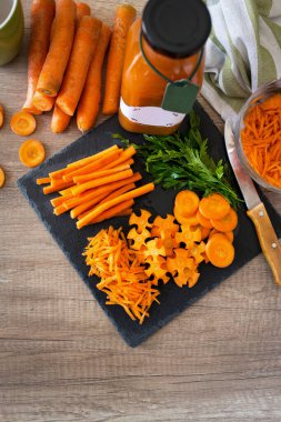 Bardakta havuç suyu ve taze havuç. Siyah taşın üstünde sağlıklı yiyecek.