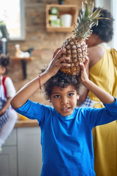 当黑人男孩站在厨房里 头上顶着一个意想不到的小饰物 菠萝时 他拥抱着自己嬉闹的精神 — 图库照片