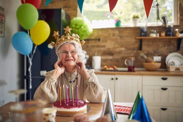 家で一人で誕生日を祝うインフレータブルクラウンを身に着けている楽しい幸せな素敵なシニア女性は 幸せな気分 ライフスタイル シニアライフコンセプト — ストック写真