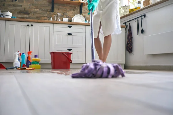 女人负责打扫厨房的地板 她精打细算地挥动拖把 毫不费力地将拖把滑过水面 清除一切污垢和污垢 — 图库照片