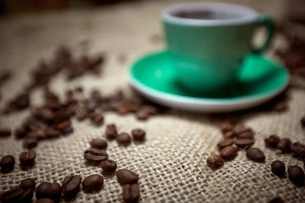 Selektiver Fokus Auf Kaffeekörner Auf Jute Mit Grüner Tasse Hintergrund — Stockfoto