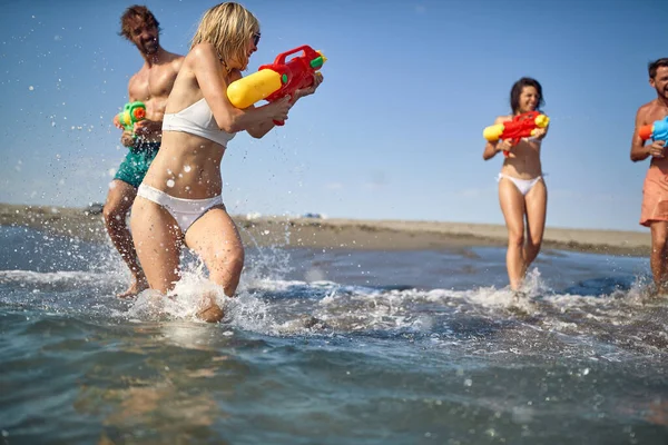 美しい夏の日に海の水のピストルで遊んでいる間 友人のグループは楽しい時間を過ごしています ビーチ — ストック写真
