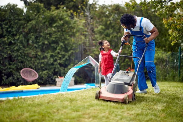 アフリカ系アメリカ人の父と彼の娘は 芝生のケアの共有活動に従事しています — ストック写真