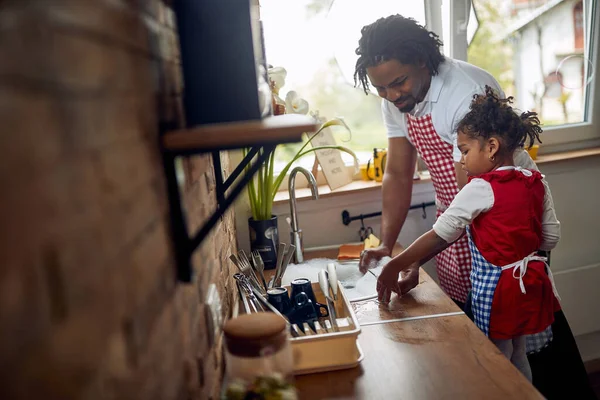 非裔美国人的父亲和他的女儿聚在一起处理洗碗的任务 他们肩并肩地站在洗碗槽边 双手浸入肥皂水中 勤勤恳恳地洗碗 — 图库照片