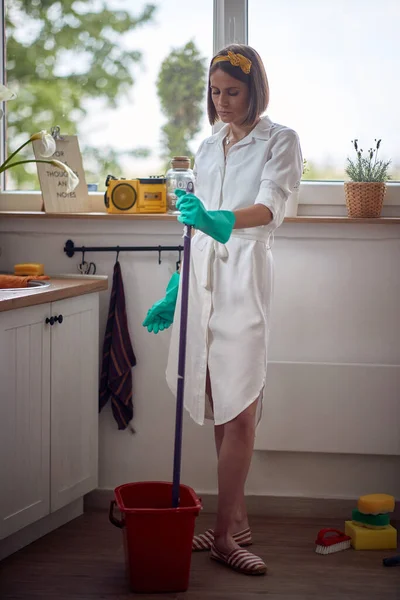 濡れた床のモップでキッチンで手袋のクリーニングを身に着けている白人の若い女性 ライフスタイルの概念 — ストック写真
