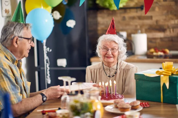 Hermosa Pareja Ancianos Felices Sentados Mesa Cocina Sombreros Cumpleaños Anciano —  Fotos de Stock