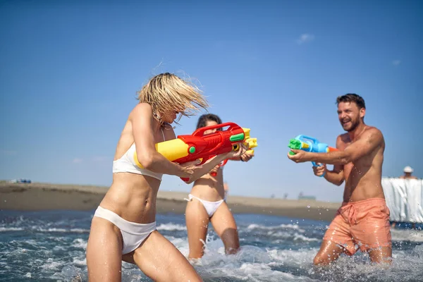 Трое Молодых Друзей Веселятся Воде Играя Водяными Пистолетами Друзья Отпуске Стоковое Изображение