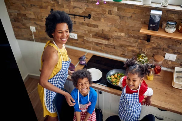 Afro-American family kitchen as the mother lovingly prepares a meal together with her delightful young son and daughter.