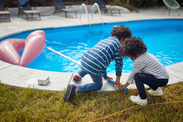 2人のアフリカ系アメリカ人の子供がプールで遊び ネットで掃除し 一緒に絆を築きました 姉妹と兄は 屋外で一緒に ファミリー ライフスタイル トータルなコンセプト ストックフォト