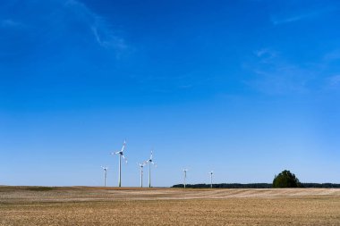 Mavi arka planda yel değirmenleri olan güzel bir tarla. Alternatif enerji kaynakları