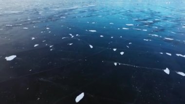 Suda kalın buz var. Balıkçılar donmuş bir gölde yürürler. Buz üzerinde desenleri olan kış manzarası