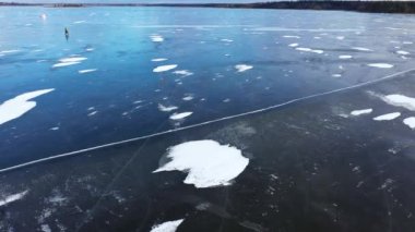 Yalnız ve cesur bir balıkçı, kalın mavi buzun üzerinde yürür. Kış balıkçılığı ve kış turizmi kavramı. Kışın açık hava eğlencesi