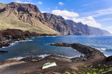 Güneşli bir günde, kayalarla ve okyanusta bir tekneyle manzara.