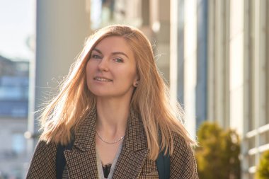 Sırt çantalı bir kız şehirde dolaşıyor. Sonbaharda bir Avrupa şehrinde zıt bir ışıkta bir iş kadınının büyük bir portresi.