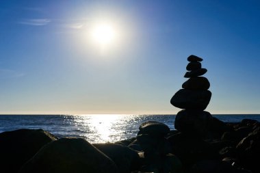 A small slide of stones against a background of blue saturated sea and sky. A picture for meditation clipart