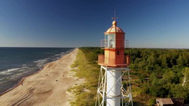 Mavi gökyüzü ve denizin arka planında parlak kırmızı bir deniz feneri. Hava fotoğrafçılığı