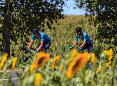 Villefranche-d'Albigeois, France - July 17th, 2022: Jeremy Lecroq and Franck Bonnamour of B&B Hotels - KTM Team, ride in the peloton near a field of sunflowers during the stage 15 of Le Tour de France 2022 clipart