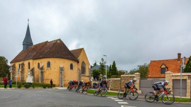 Meslay-le-Grenet, Fransa - 27 Eylül 2024: Tur Eure-et-Loir 'in 2024 sayısında Meslay-le-Grenet' deki ünlü antik bir kilisenin önündeki pelotonun görüntüsü.