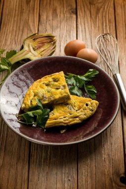 slice omelet with artichoke over wooden table