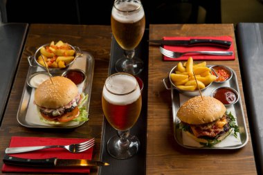 Restoran masasında patates ve birayla hamburger.