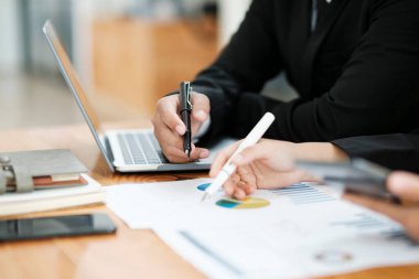 İş adamları ya da iş arkadaşları iş yerlerinde dizüstü bilgisayar ve grafikler kullanarak proje üzerinde birlikte çalışır, tartışır, fikir paylaşır, plan yapar ve iş stratejisi ve finansmanı analiz ederler..