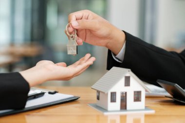 Emlakçı başarılı bir pazarlıktan sonra ev anahtarını müşteriye veriyor ve ev almak için sigorta sözleşmesi imzalıyor. Emlak kavramı.